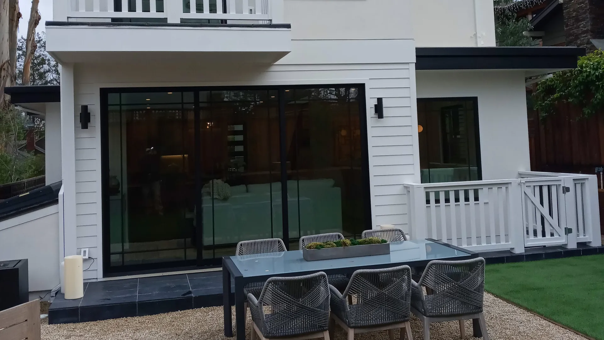 Modern home patio with floor-to-ceiling sliding glass doors and outdoor dining